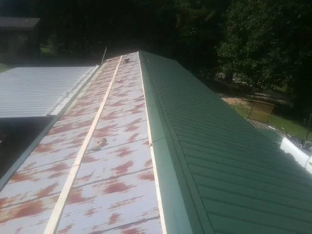 Old rusted panels beside newly installed green metal roofing — Wind Damage Roof Repair by Roofing Brothers in Brunswick